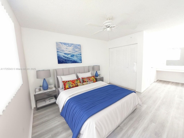 bedroom featuring ceiling fan, a textured ceiling, baseboards, wood finished floors, and a closet