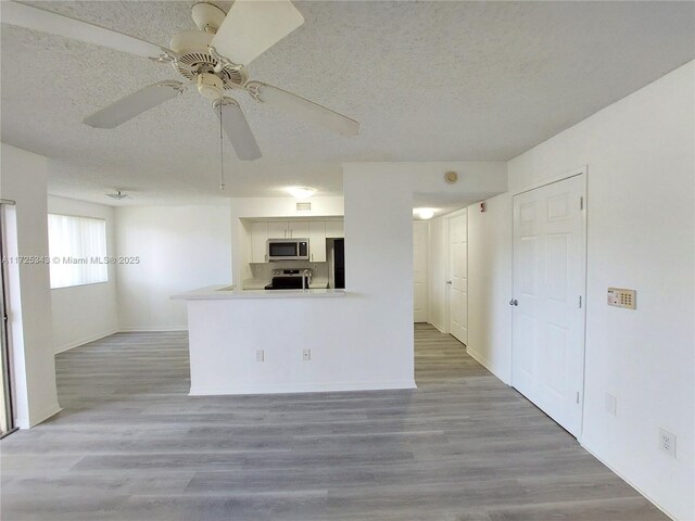 kitchen featuring white cabinetry, hardwood / wood-style flooring, kitchen peninsula, stainless steel appliances, and a textured ceiling