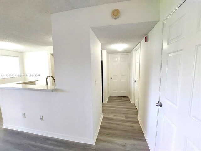 hall with sink, dark wood-type flooring, and a textured ceiling