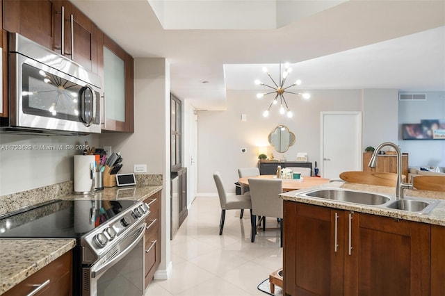 kitchen with light stone counters, a chandelier, appliances with stainless steel finishes, light tile patterned flooring, and sink