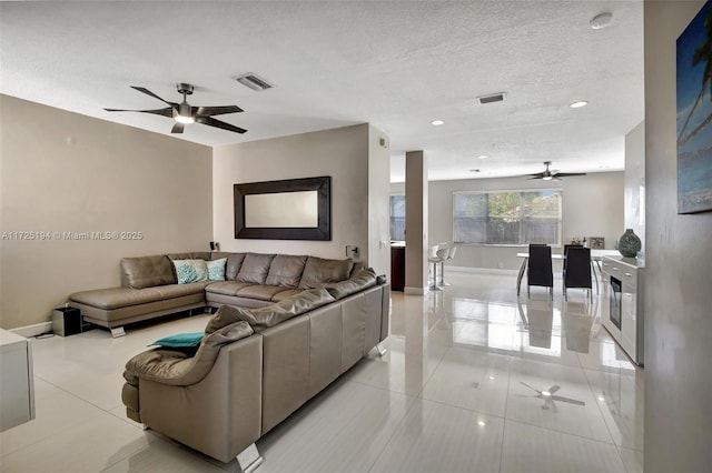 tiled living room featuring ceiling fan and a textured ceiling