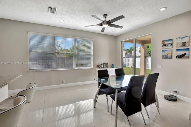 tiled dining area with ceiling fan and a textured ceiling