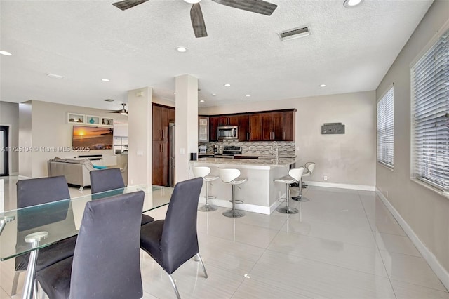 dining area featuring a textured ceiling, ceiling fan, and light tile patterned flooring