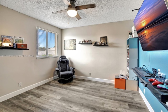 living area featuring ceiling fan, hardwood / wood-style floors, and a textured ceiling