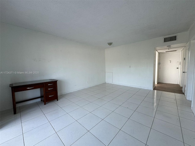 spare room featuring a textured ceiling and light tile patterned floors