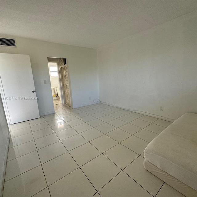 tiled spare room with a textured ceiling