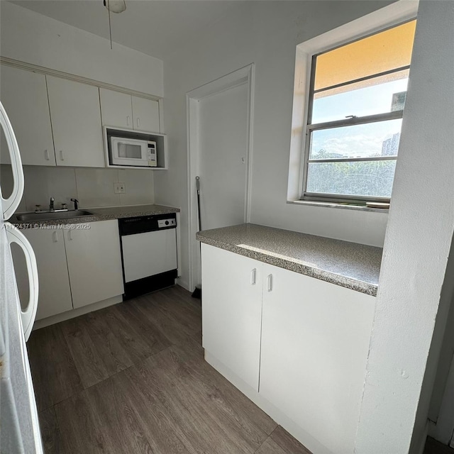 kitchen with white appliances, dark wood-type flooring, white cabinets, and sink