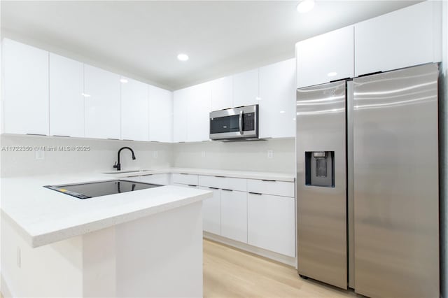 kitchen featuring sink, white cabinets, light wood-type flooring, and appliances with stainless steel finishes