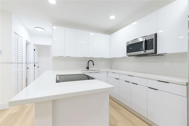 kitchen featuring sink, white cabinetry, black electric cooktop, and light hardwood / wood-style floors