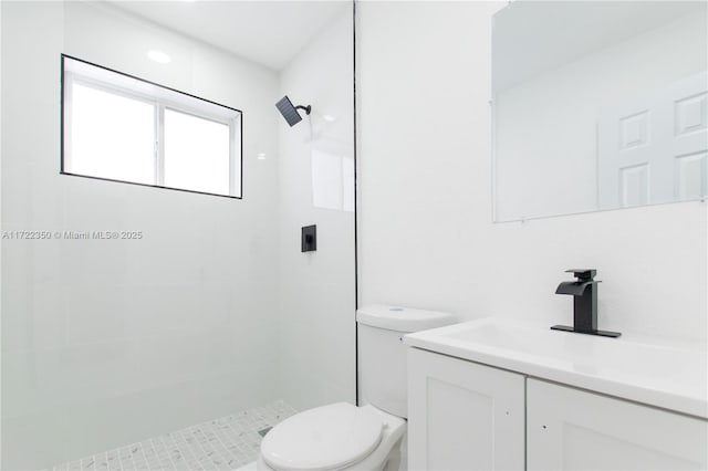 bathroom featuring toilet, tiled shower, and vanity