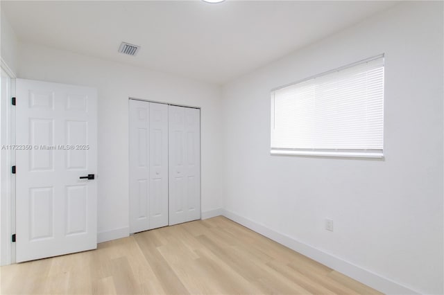 unfurnished bedroom with a closet and light wood-type flooring