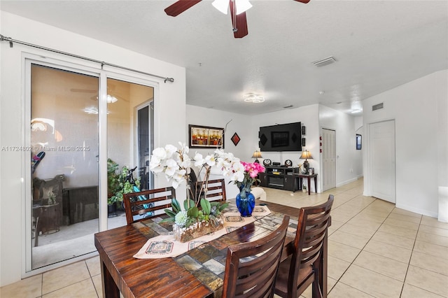 tiled dining area with ceiling fan and a textured ceiling