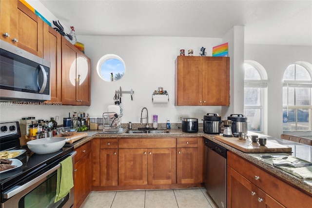 kitchen with light stone counters, appliances with stainless steel finishes, sink, and light tile patterned floors