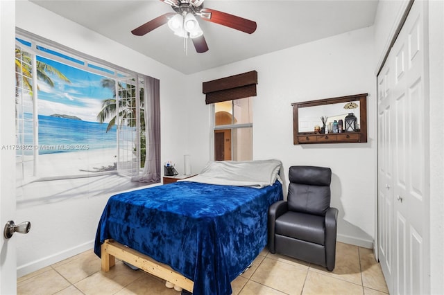 bedroom with light tile patterned flooring, ceiling fan, and a closet