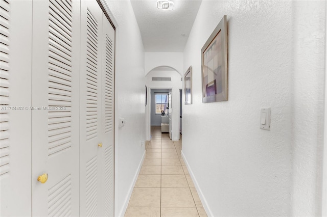 corridor featuring a textured ceiling and light tile patterned flooring