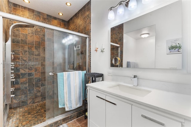 bathroom featuring a shower with door and vanity