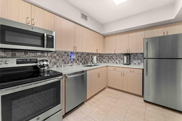 kitchen with backsplash, stainless steel appliances, light brown cabinets, sink, and light tile patterned flooring