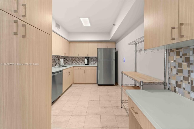 kitchen featuring appliances with stainless steel finishes, light tile patterned floors, light brown cabinets, sink, and tasteful backsplash