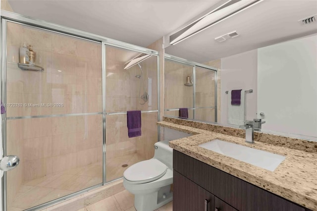 bathroom featuring toilet, vanity, tile patterned flooring, and a shower with shower door