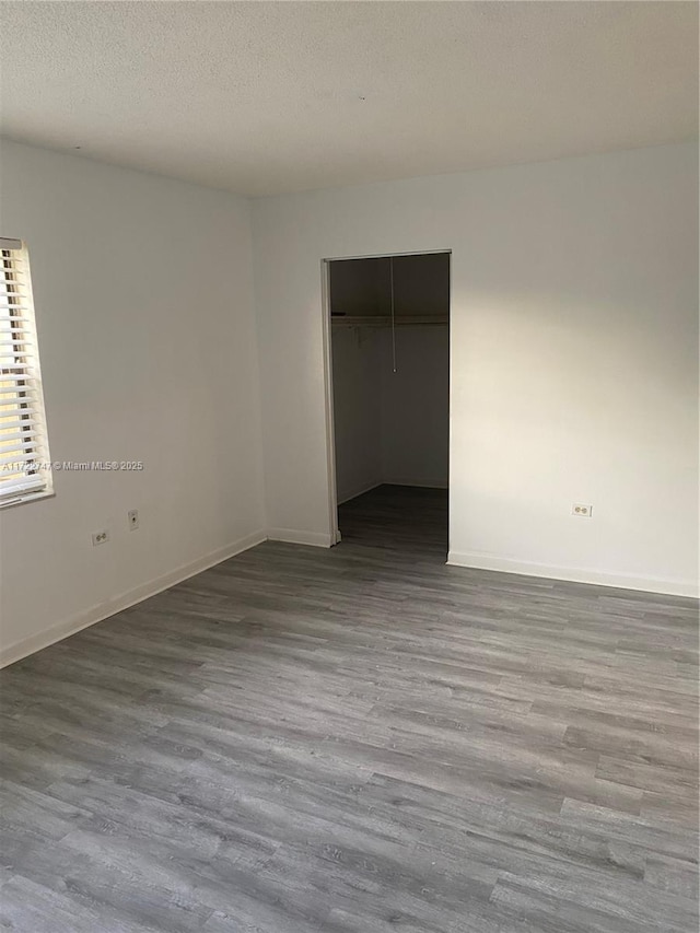 unfurnished bedroom featuring a textured ceiling, a closet, and hardwood / wood-style flooring