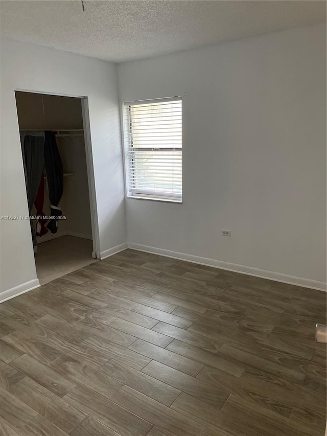 unfurnished bedroom with a closet, a textured ceiling, and dark wood-type flooring