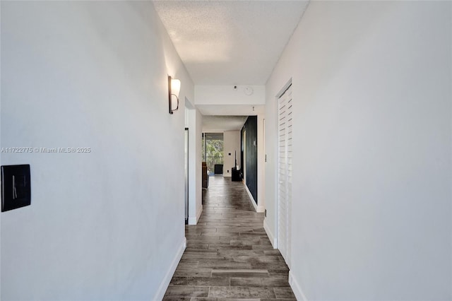 hall featuring dark wood-type flooring and a textured ceiling