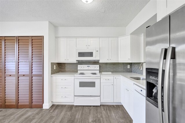 4570 NW 18th Ave Unit 202, Deerfield Beach, FL 33064 - kitchen featuring white appliances, light wood-style floors, light countertops, tasteful backsplash, and white cabinets