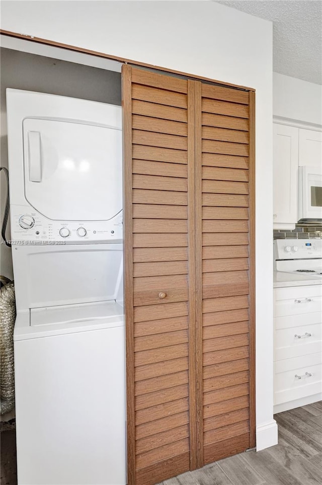 laundry area featuring stacked washer and clothes dryer, a textured ceiling, and dark hardwood / wood-style floors