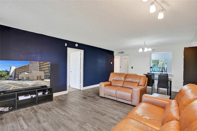 living room with a textured ceiling, an inviting chandelier, and hardwood / wood-style flooring