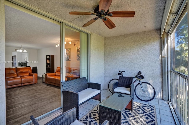 sunroom featuring ceiling fan with notable chandelier