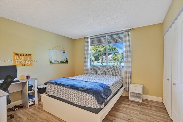 bedroom featuring a textured ceiling, light hardwood / wood-style flooring, and a closet