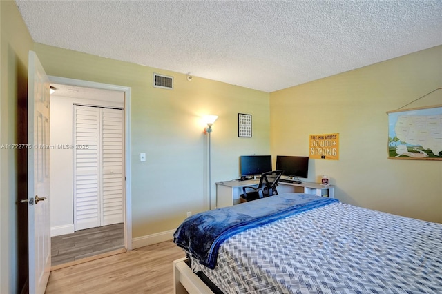 bedroom with a textured ceiling and light hardwood / wood-style floors