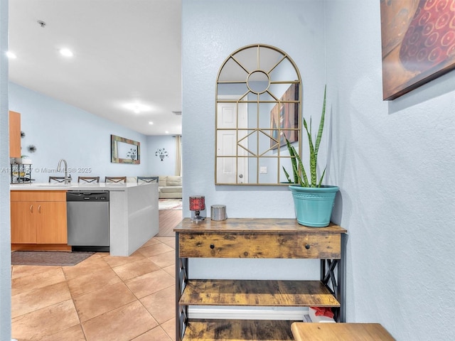 kitchen with stainless steel dishwasher, light tile patterned floors, and sink