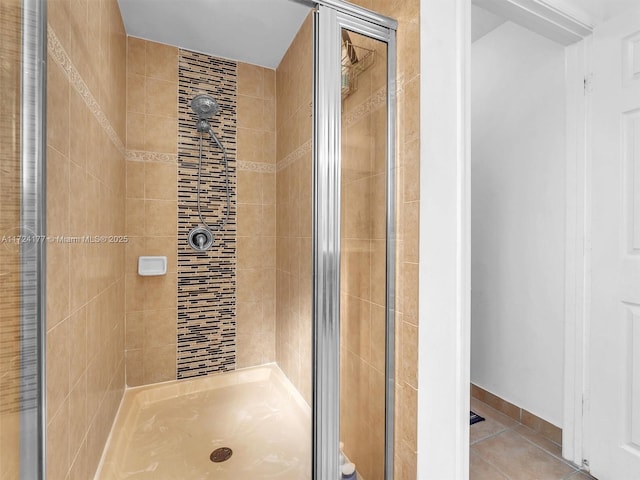 bathroom with a shower with door and tile patterned flooring