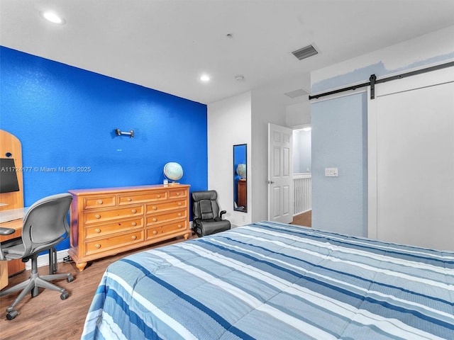 bedroom featuring hardwood / wood-style floors and a barn door