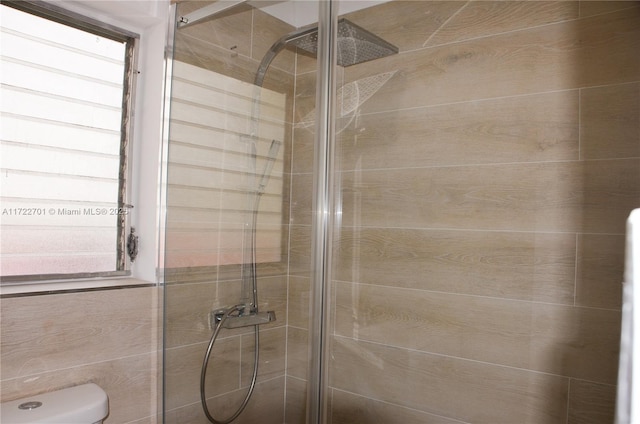 bathroom featuring a shower with door and toilet