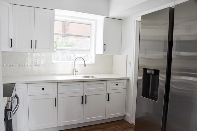 kitchen with white cabinets, stainless steel fridge, tasteful backsplash, and sink