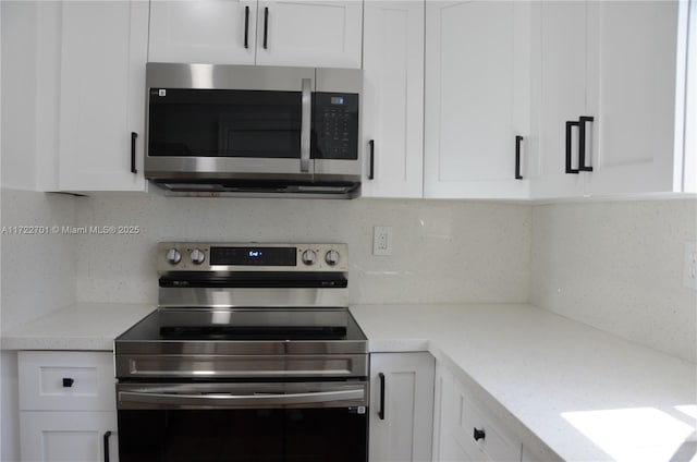 kitchen featuring stainless steel appliances, white cabinets, and tasteful backsplash