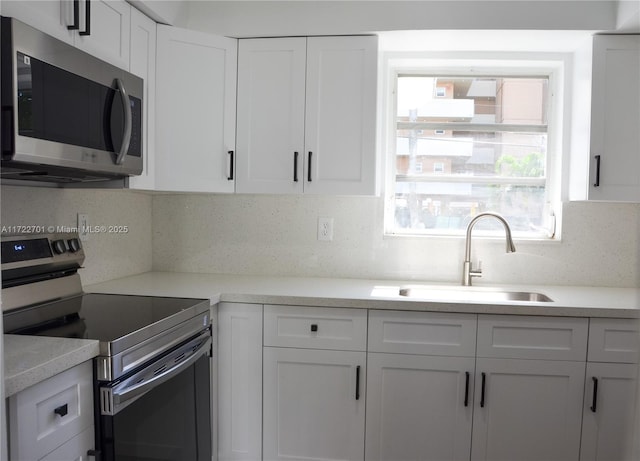 kitchen with sink, stainless steel appliances, tasteful backsplash, and white cabinetry