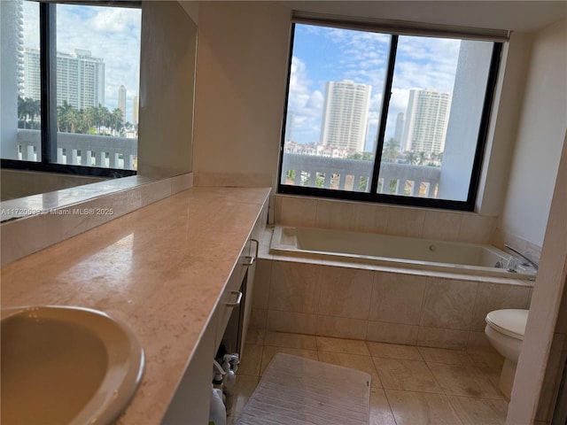 bathroom with vanity, tile patterned flooring, toilet, and tiled tub