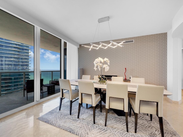 dining space with expansive windows and a water view