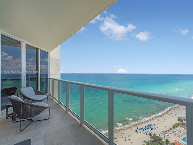 balcony featuring a water view and a view of the beach