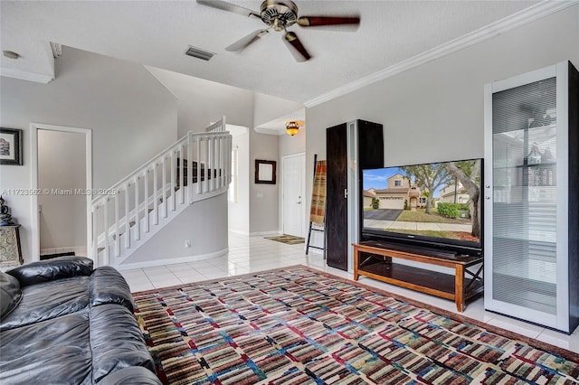 living room with light tile patterned floors, ornamental molding, a textured ceiling, and ceiling fan