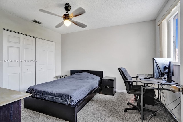 bedroom with ceiling fan, light colored carpet, a textured ceiling, and a closet