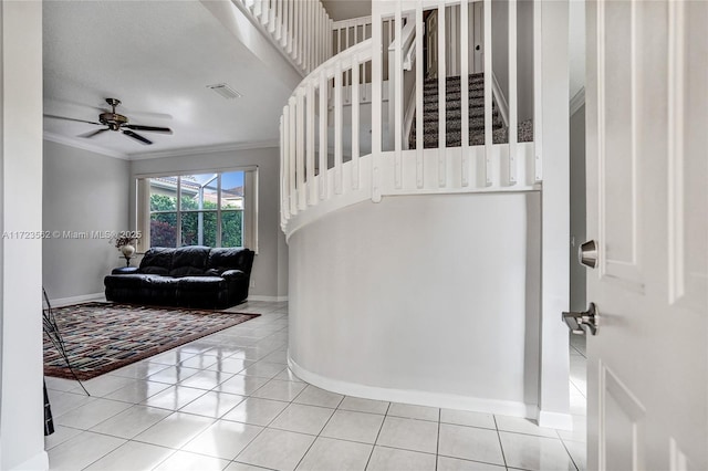 stairs with tile patterned flooring, ornamental molding, and ceiling fan