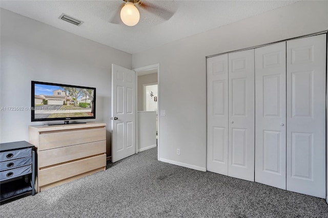 unfurnished bedroom with ceiling fan, a closet, dark carpet, and a textured ceiling