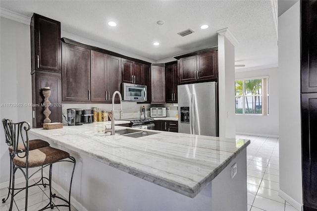 kitchen with appliances with stainless steel finishes, a kitchen bar, kitchen peninsula, and sink