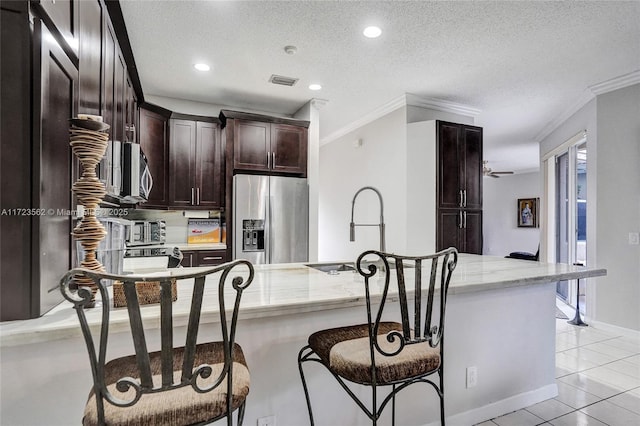 kitchen featuring stainless steel appliances, sink, a textured ceiling, and kitchen peninsula