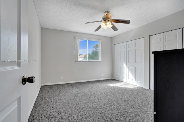 unfurnished bedroom featuring ceiling fan, carpet flooring, two closets, and a textured ceiling