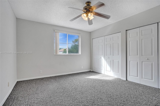 unfurnished bedroom with ceiling fan, a textured ceiling, multiple closets, and carpet flooring